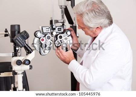 Doctor in ophthalmology clinic adjusting phoropter.