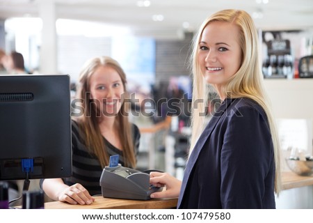 Receptionist and client in beauty salon paying with credit card.