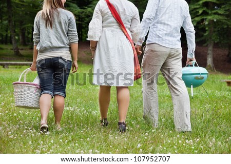 Rear view of friends in casual wear on a weekend picnic in forest park