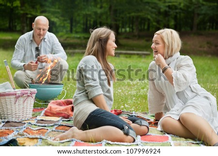 Friends visiting and preparing a barbecue for outdoor picnic