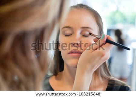 close up of beautician applying eye shadow to woman at parlor