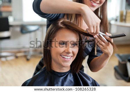 Happy young woman getting a new haircut by hairdresser at parlor