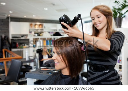 Beautician blow drying woman's hair after giving a new haircut at parlor Beautician blow drying woman's hair after giving a new haircut at parlor
