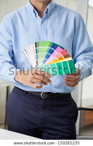 Midsection of male interior designer holding fanned out color swatches