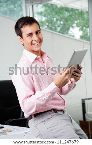 Portrait of happy young male business executive holding digital tablet