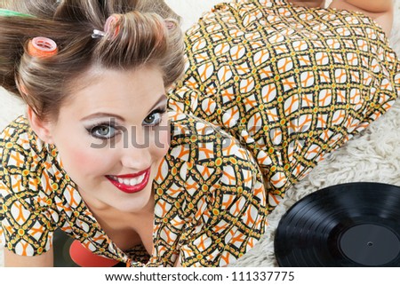 High angle view of beautiful young woman in hair curlers lying on rug beside vinyl records