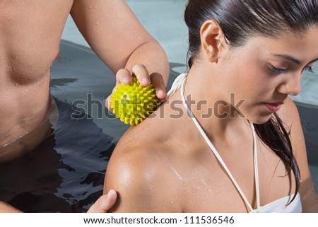 Young mixed race woman receiving back massage with stress ball by male therapist