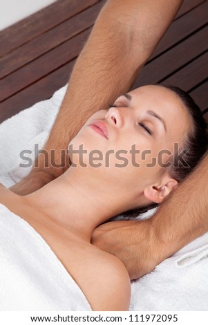 Pretty young female relaxing with eyes closed as she receives massage at health spa