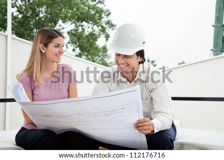 Young female client discussing house plan with male architect