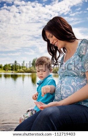Portrait of happy mother and son playing outdoors near pond