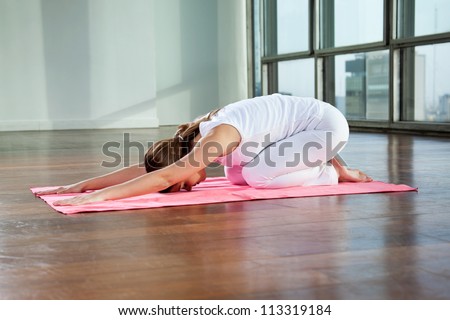 Full length of a young woman sitting in child\'s pose on a yoga mat