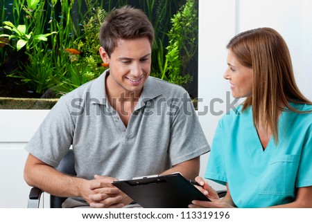 Female dentist with clipboard explaining something to man in clinic
