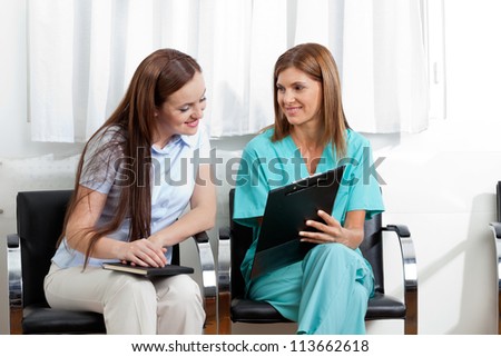 Female dentist showing something to young patient on clipboard in clinic