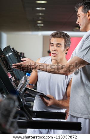 Man asking instructor about machines at health club