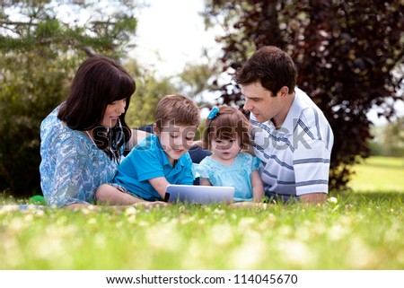 Happy family of four using a digital tablet outdoors