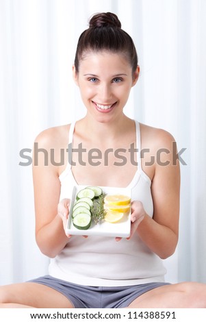 Young woman holding salad in tray.