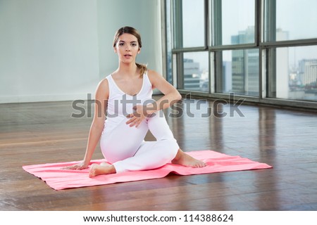 Full length of a young woman in Half Spinal Twist pose on mat