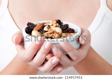 Close-up of woman holding bowl of dry fruits.