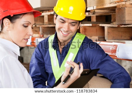 Female supervisor showing clipboard to young foreman at warehouse