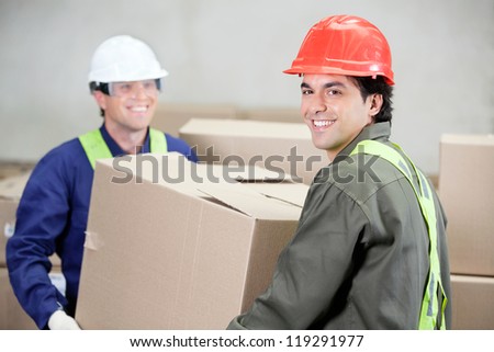 Two foremen lifting cardboard box at warehouse