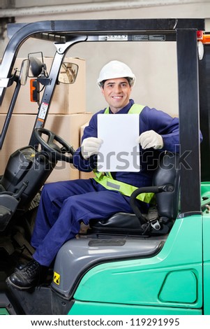 Portrait of happy forklift driver displaying blank placard