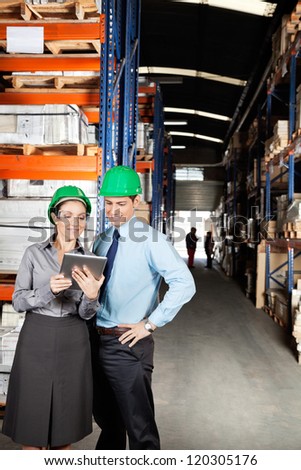Female supervisor and colleague using digital tablet at warehouse