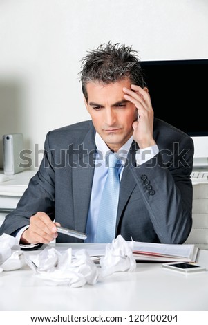 Tensed businessman sitting at desk in office