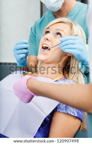 Two dentists treating a young female patient at clinic