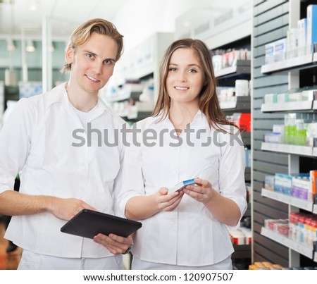 Portrait of happy young pharmacists with digital tablet in pharmacy
