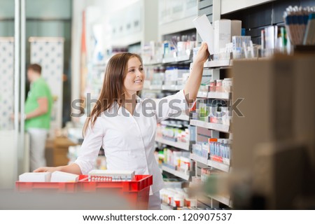 Young pharmacist stocking shelves in pharmacy