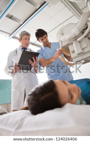Radiologist with male technician sets up the machine to x-ray female patient