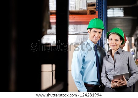Portrait of two young supervisors with digital tablet smiling together at warehouse