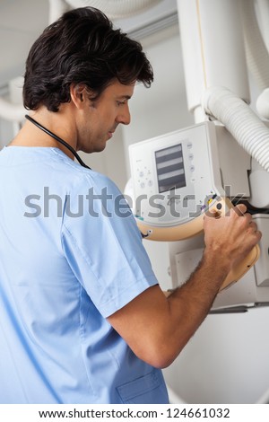 Mixed race male technician in uniform operating x-ray machine