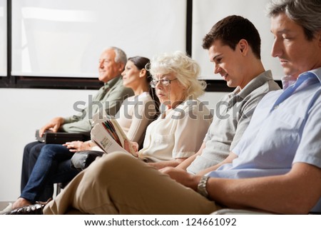 Row of multiethnic people waiting for the doctor in hospital lobby Row of multiethnic people waiting for the doctor in hospital lobby