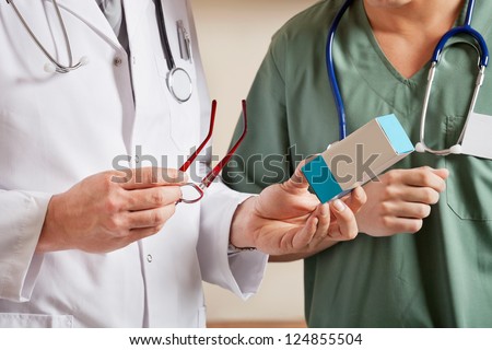 Midsection of male doctor holding medicine box while standing with technician