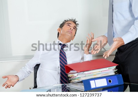 Mid adult businessman at desk overwhelmed by load of work