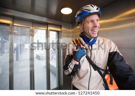 Young man in protective gear with courier delivery bag in an elevator