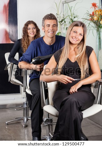 Portrait of confident team of hairstylists sitting at beauty parlor