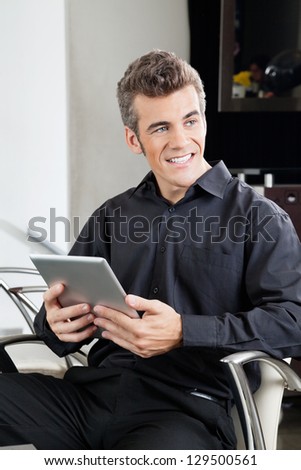 Male customer with digital tablet waiting in hair salon