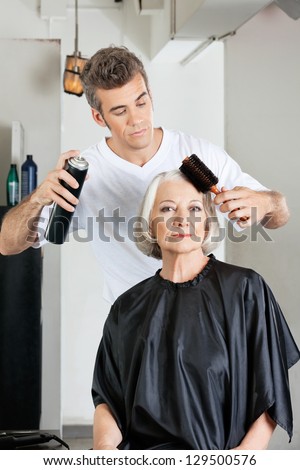 Portrait of senior woman with hairdresser styling her hair at salon