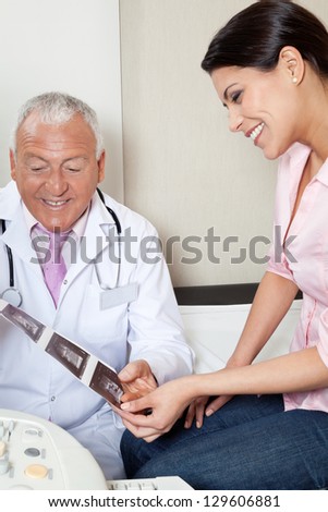 Senior male radiologist showing ultrasound print to female patient