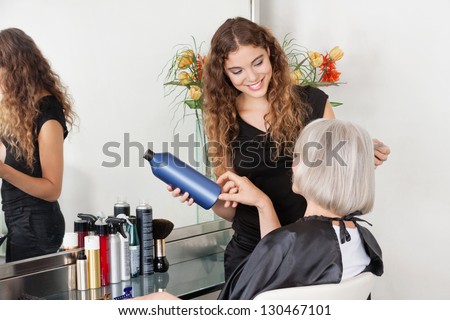 Female hairstylist advising hair color to senior client at beauty parlor