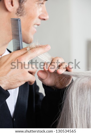 Closeup of male hairdresser cutting senior woman\'s hair at hair salon