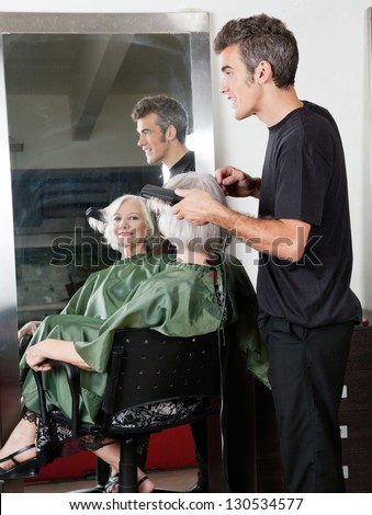 Male hair stylist straightening female customer\'s hair in salon