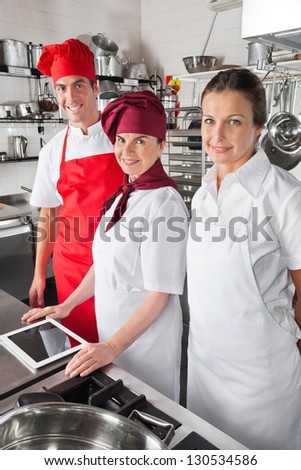 Portrait of happy chefs with digital tablet in commercial kitchen