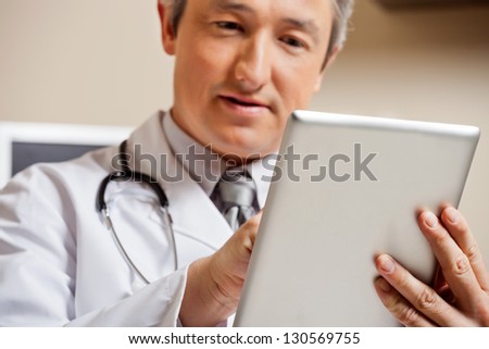 Close up of mature male doctor using digital tablet