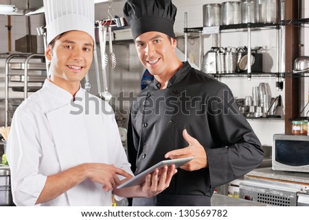 Portrait of young male chefs holding digital tablet in commercial kitchen