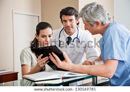 Portrait of mixed race doctor with colleague and female receptionist in hospital reception