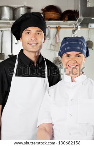 Portrait of happy chefs standing in industrial kitchen