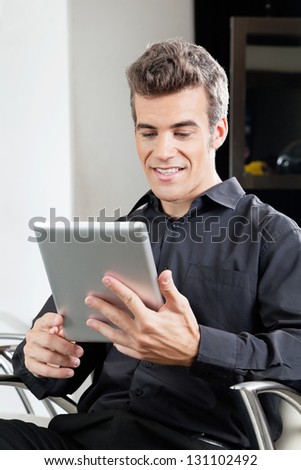 Male client using digital tablet while waiting in hair salon